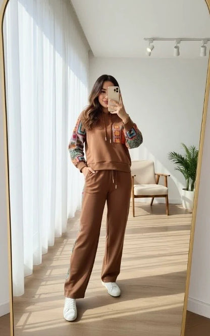 Chakoor women taking a mirror selfie wearing a brown sweatshirt and pants in a bright room.
