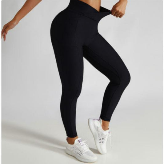 A person standing and posing in black yoga fitness tights and white shoes.